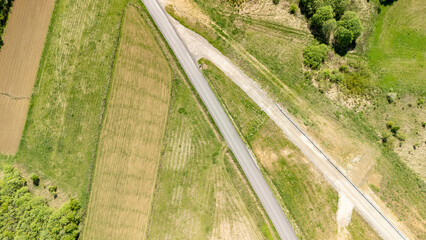 Aerial view of a rural landscape featuring patchwork fields and a winding road. The scene captures...