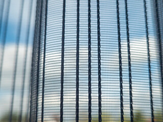 Close-up view of a mesh curtain with sunlight filtering through, casting soft shadows. The scene...