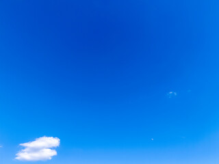 A clear blue sky with a few white clouds floating gently, creating a serene and peaceful...