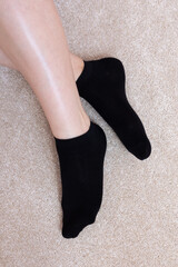Female feet in black socks on carpet