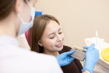 The dentist selects the color of the enamel. The dentist selects a shade of tooth enamel using a...