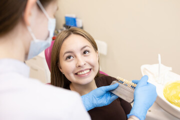 The dentist selects the color of the enamel. The dentist selects a shade of tooth enamel using a...