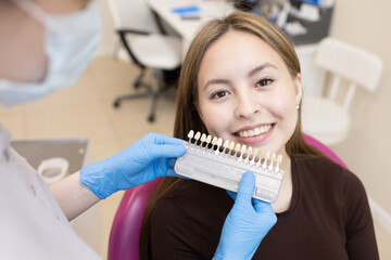The dentist selects the color of the enamel. The dentist selects a shade of tooth enamel using a...
