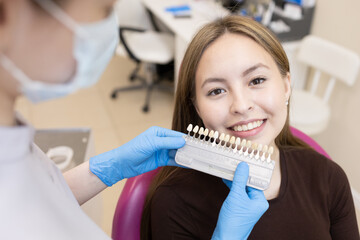 The dentist selects the color of the enamel. The dentist selects a shade of tooth enamel using a...
