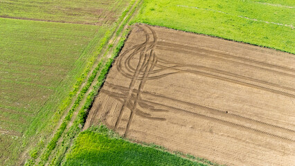 Aerial view of agricultural land showing contrasting green fields and freshly plowed brown soil...