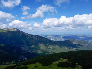 Scenic view of mountains under a blue sky filled with clouds, highlighting dense forests and...