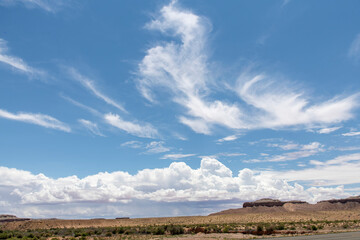 Cloudscape of feather clouds and cumulus clouds above the rock formations in the desert south of Green River, UT, USA along the Utah State Route 24