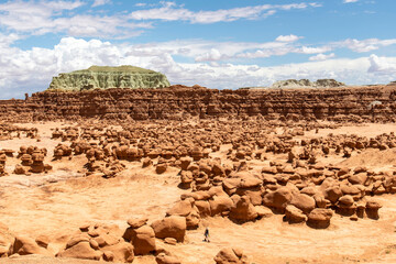One person walkin between mushroomlike sandstone rock formations called goblins and eroded cliffs...