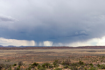 Panoramic view over the landscape of Arches National Park, Utah, USA with cloudscape of dark clouds and streaks, curtains or Virga of precipitation falling from the clouds