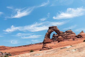 Panoramic view over area of landmark geological sandstone formation of Delicate arch against a blue sky with feather clouds in Arches National Park, Moab, UT, USA