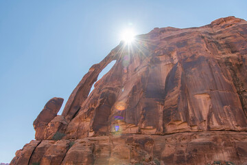 Geological sandstone formation Jug Handle Arch with bright sun and sun rays over the top along the Potash Road along the Colorado River near Moab, Utah, USA