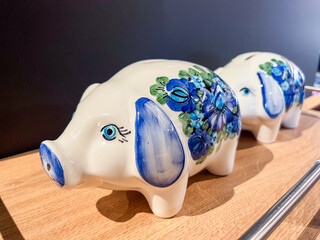 Decorative ceramic piggy banks adorned with blue floral patterns, placed on a wooden surface,...