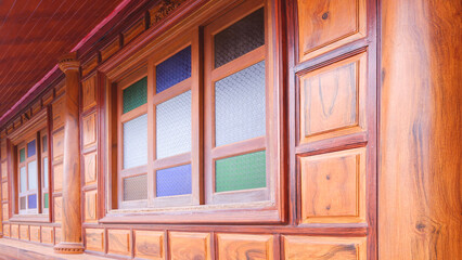 Wooden house in vintage retro style with multicolored stained glass window on teak wood wall background, perspective side view