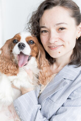 a woman holds a King Charles spaniel in her arms