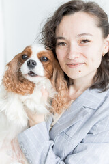 a woman holds a King Charles spaniel in her arms