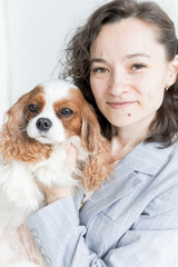 a woman holds a King Charles spaniel in her arms