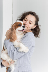 a woman holds a King Charles spaniel in her arms