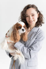 a woman holds a King Charles spaniel in her arms