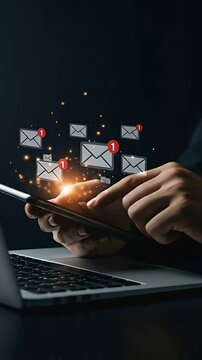 Checking New Emails: Business man in a suit scrolls on his smartphone next to a laptop to read new messages with email notifications icons.