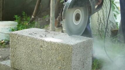 Worker cutting cinder block with angle grinder