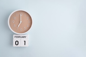 February 1st.Wooden calendar with the date February 1 and a clock on a colored background with copy...