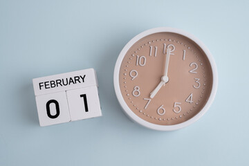 February 1st.Wooden calendar with the date February 1 and a clock on a colored background with copy...
