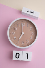 June 1st. Wooden calendar with the date June 1 and a clock on a colored background with copy space....