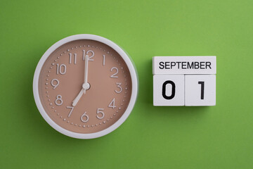 September 1st.Wooden calendar with the date September 1 and a clock on a colored background with...