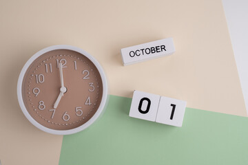 October  1st.Wooden calendar with the date October 1 and a clock on a colored background with copy...
