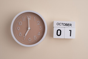 October  1st.Wooden calendar with the date October 1 and a clock on a colored background with copy...