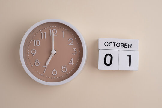 October  1st.Wooden calendar with the date October 1 and a clock on a colored background with copy space. First spring day. Empty space for text