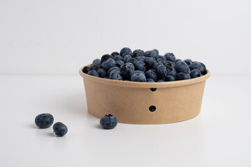 Fresh organic blueberries in a plate on a light background. Antioxidants and vitamins