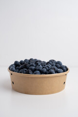 Fresh organic blueberries in a plate on a light background. Antioxidants and vitamins