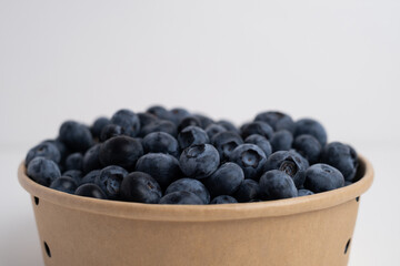 Fresh organic blueberries in a plate on a light background. Antioxidants and vitamins