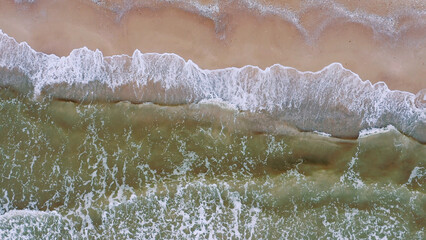 Aerial view of waves on a sandy tropical beach.