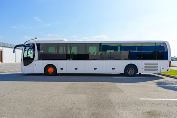 A large long tourist bus is parked, side view