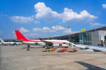 A busy airport is bustling with activity as cargo is being loaded onto commercial airplanes. The...