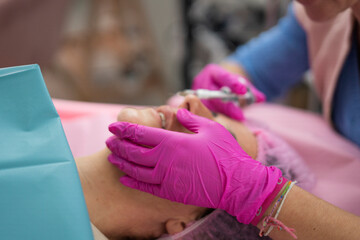 Beautician applying permanent makeup on lips of client