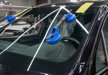 Automobile special workers replacing windscreen or windshield of a car in auto service station...