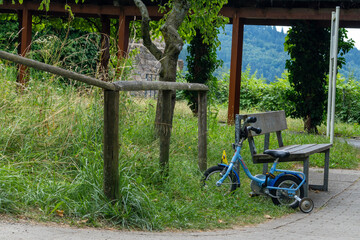 Blue Child's Bicycle With Supporting Wheels Near Wooden Park Bench Outdoors