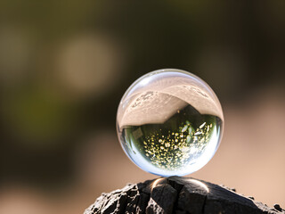 A clear glass ball is sitting on a wooden surface