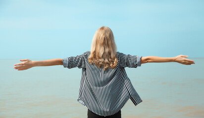 Summer vacation, happy inspired young woman raising her hands up on the beach, relaxed girl on sea