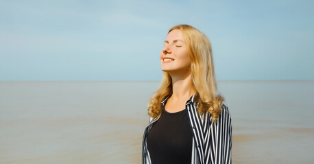 Calm relaxing young woman meditates, happy girl practicing breathing exercises on beach on sea