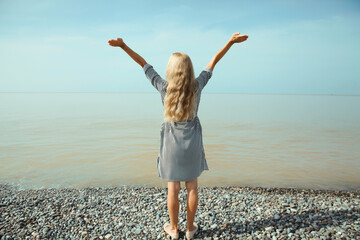 Summer vacation, happy inspired young woman raising her hands up on the beach, relaxed girl on sea