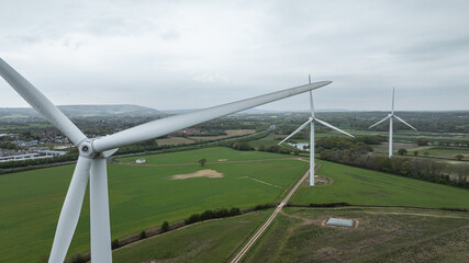 Wind turbines stand tall in a green field, symbolizing clean, sustainable power production, East Sussex, UK