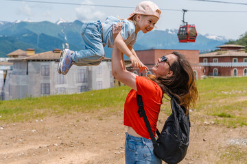 A young mother with her three-year-old child daughter goes to the mountains on Krasnaya Polyana in...