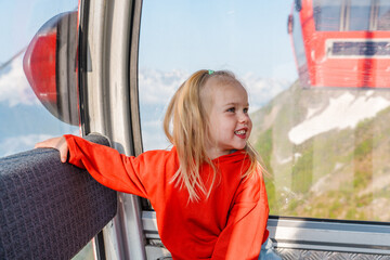 A three-year-old child girl travels in the mountains in the summer, rides a funicular, Krasnaya...