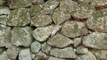 Ancient wall stone masonry in fence around the house, large and small stones.