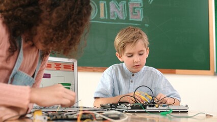 Caucasian smart boy fixing main board by using screwdriver at stem technology lesson while smiling...