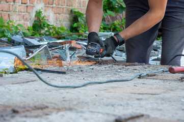 Sparks fly as a worker expertly cuts through rubble and debris, showing focused effort in a...